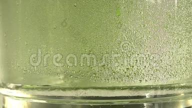 纯净水或酒精滴在玻璃罐内，绿色背景。 蒸馏过程。 特写